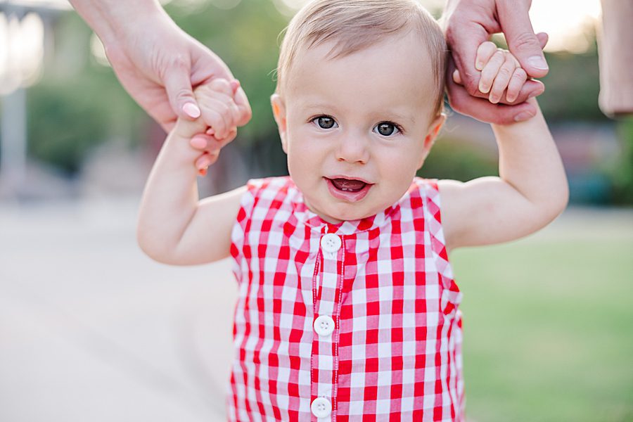 baby standing between mom and dad