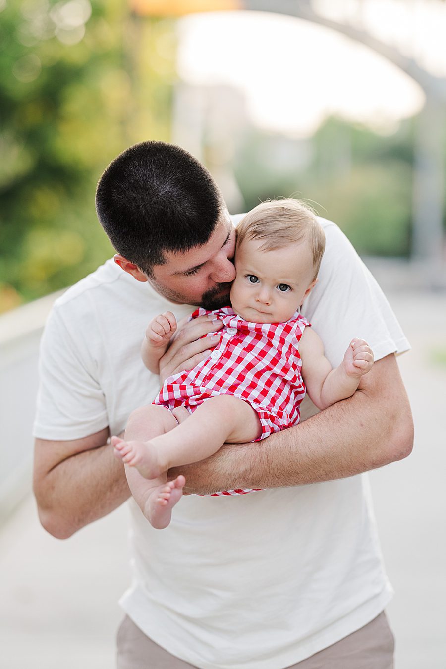 dad holding son in red gingham overalls