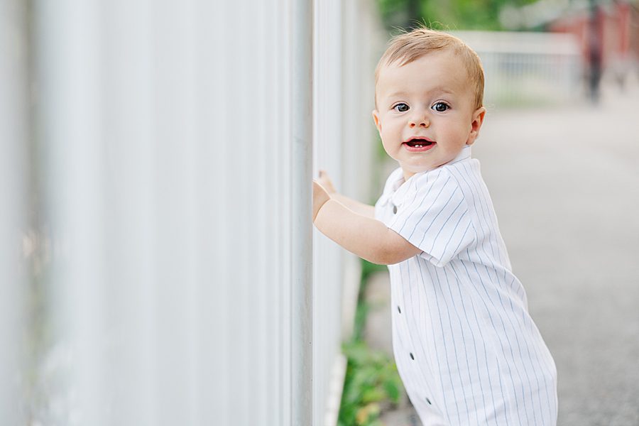 little boy standing by fence at baby's first year session