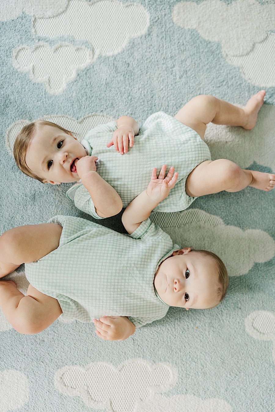 babies laying on blue rug at baby's first year session