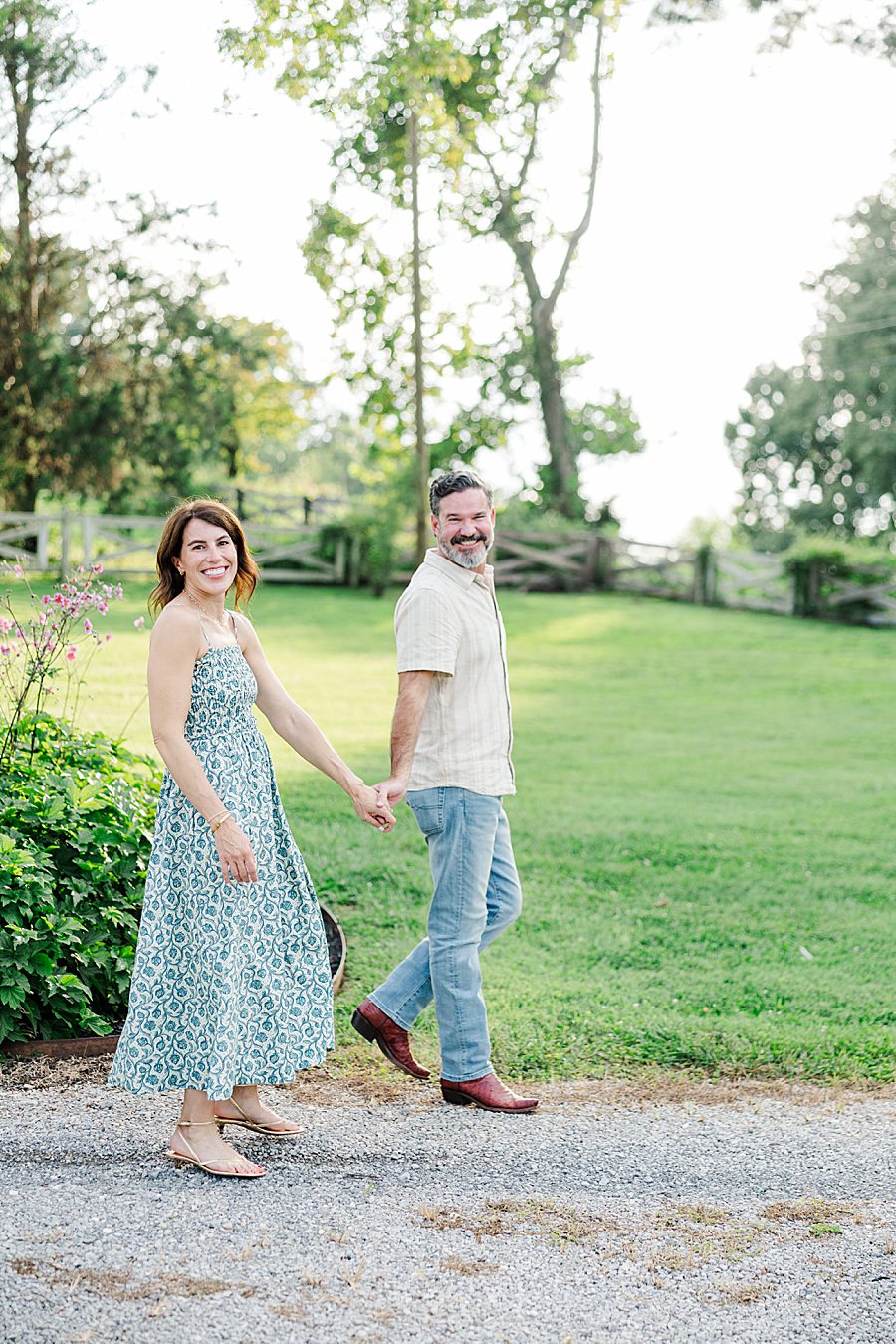 man and woman holding hands and walking during horse farm engagement session