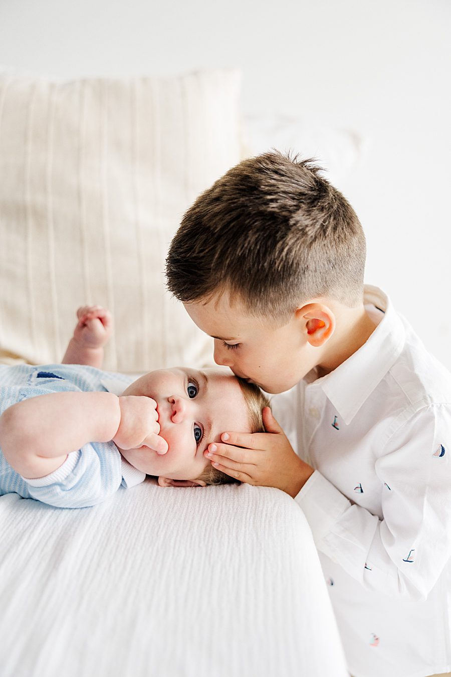 boy kissing baby brother's forehead