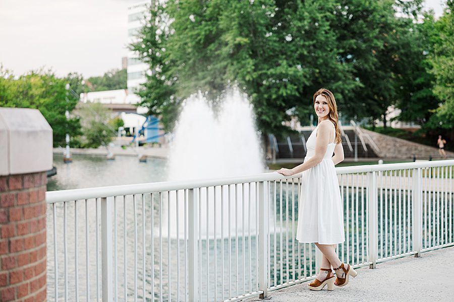 woman in white dress by water fountain at colorful stairs senior session