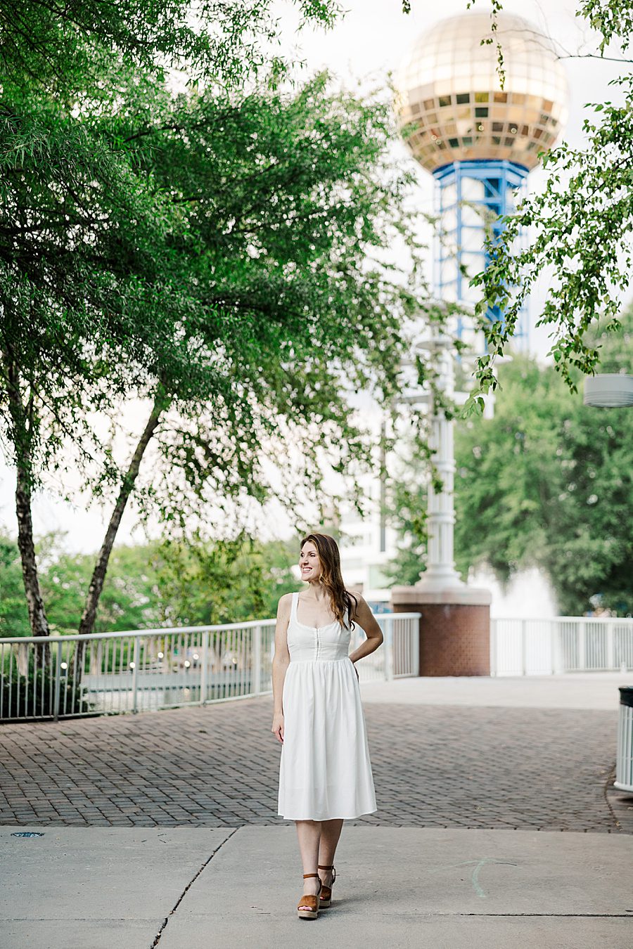 woman in white sundress in front of sunsphere at world's fair site