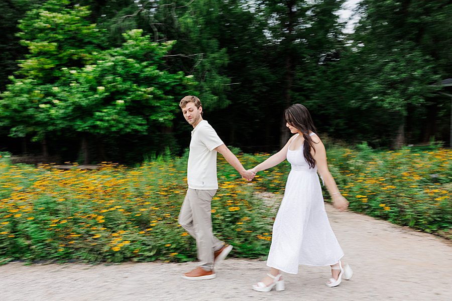 couple holding hands and walking along path