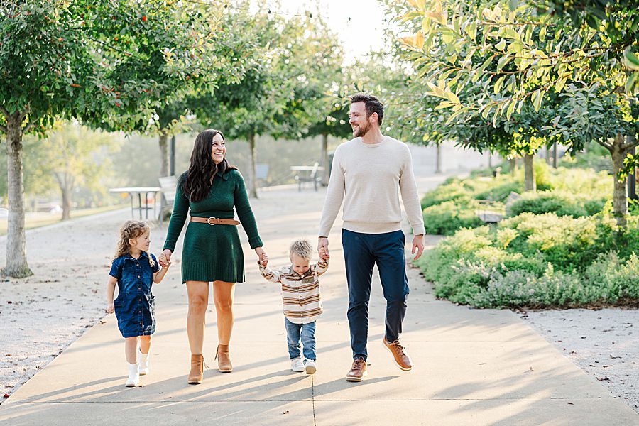 family of four holding hands and walking during lakeshore family session