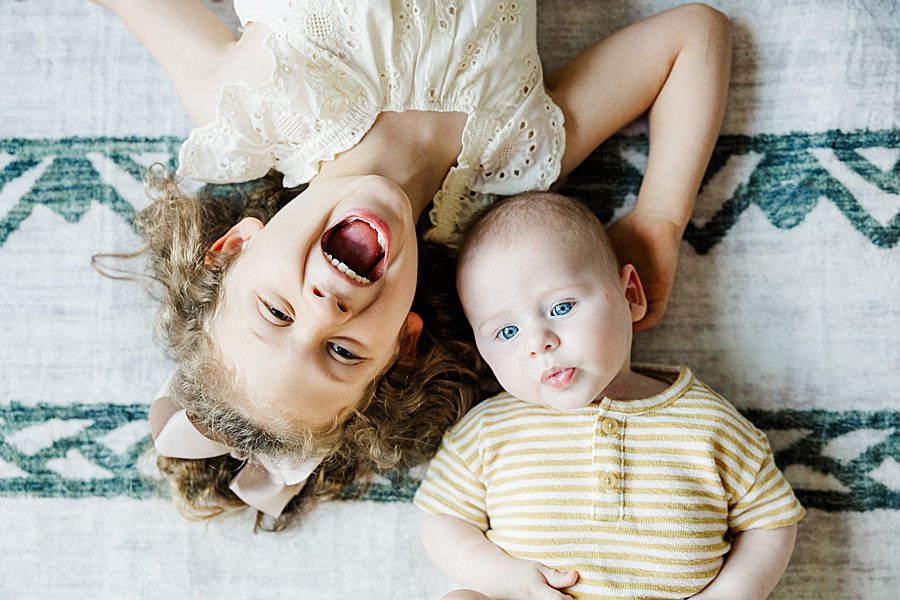 brother and sister laying on nursery rug at powell home milestone session