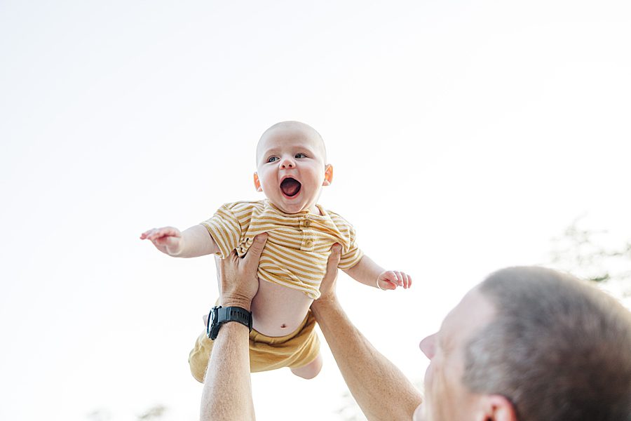 dad playing with baby boy dressed in yellow