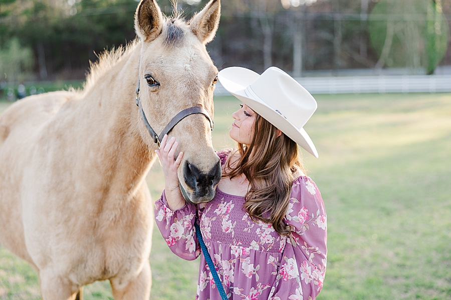 girl in white cowboy hat looking at horse