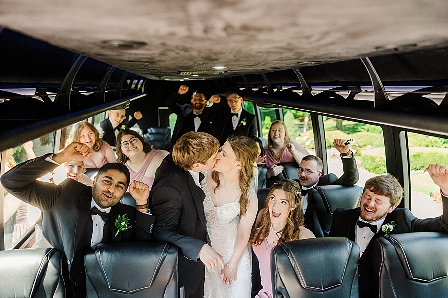 Bride and groom kiss while wedding party cheers at wedding by Amanda May Photos