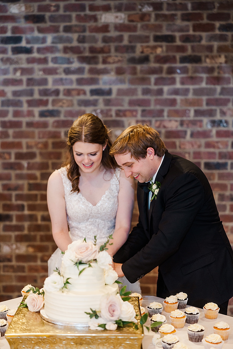 Couple cutting cake at wedding by Amanda May Photos