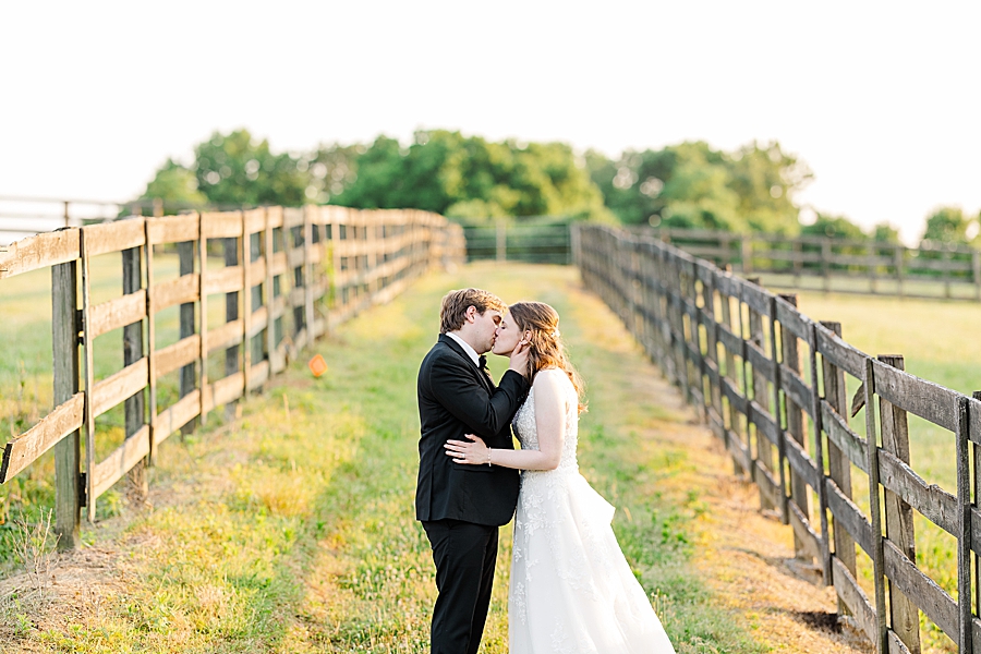 Kissing between the fences at wedding by Amanda May Photos