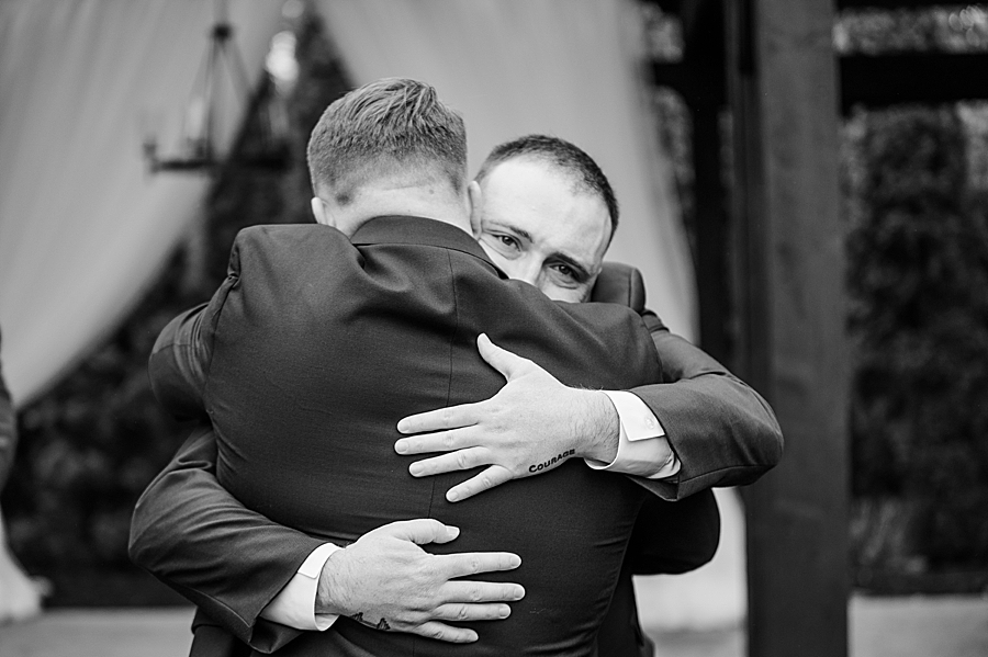 Groom hugging groomsmen at Wedding by Amanda May Photos