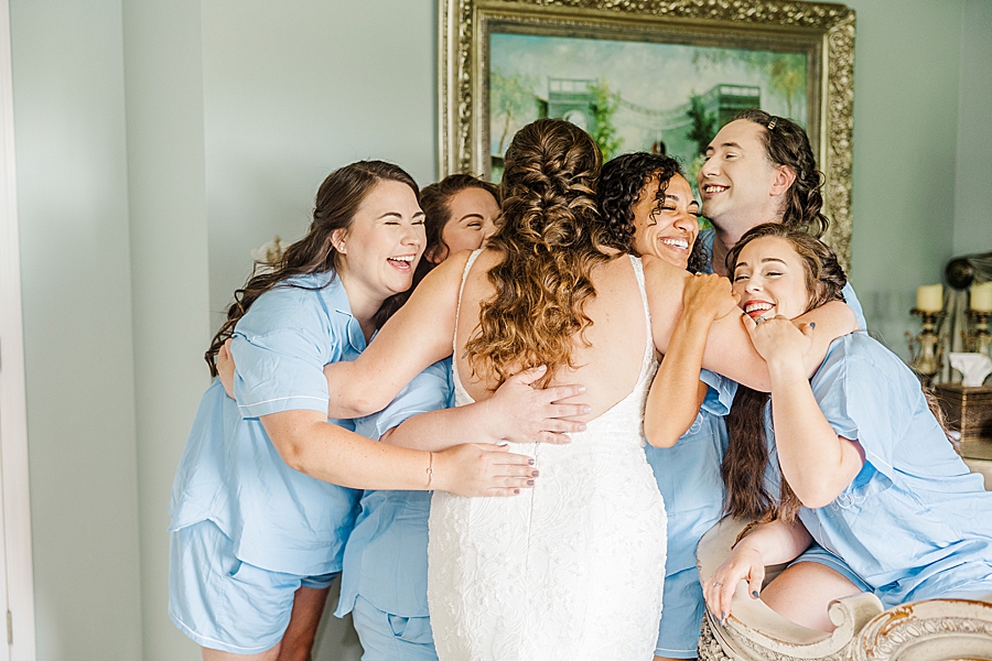 Bride hugging bridesmaids at Castleton Farms Wedding with a Rainbow by Amanda May Photos