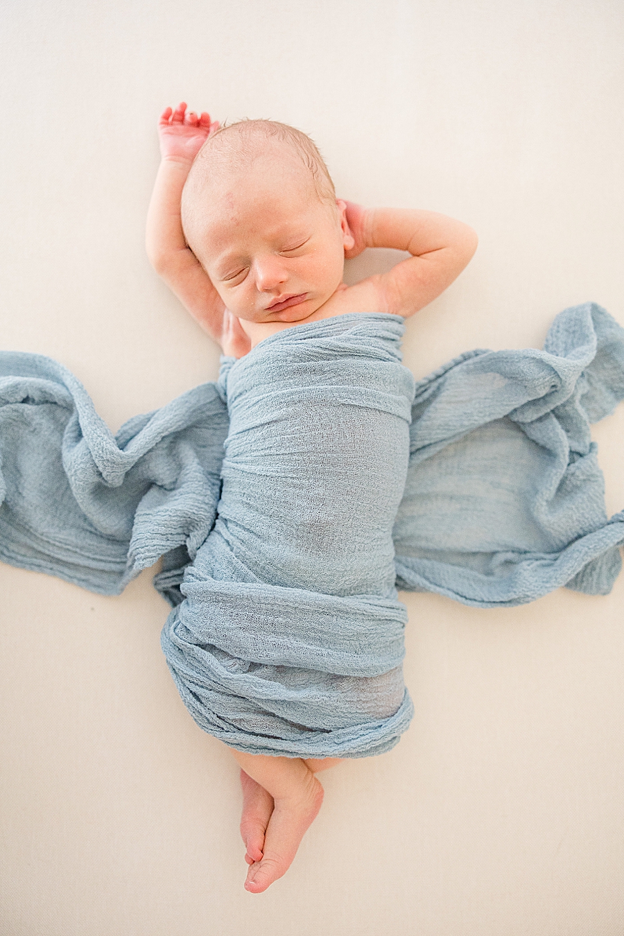 baby in blue swaddle stretching
