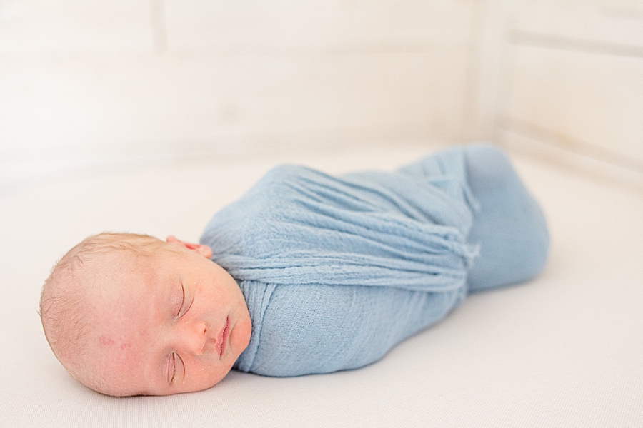 newborn baby sleeping in blue swaddle