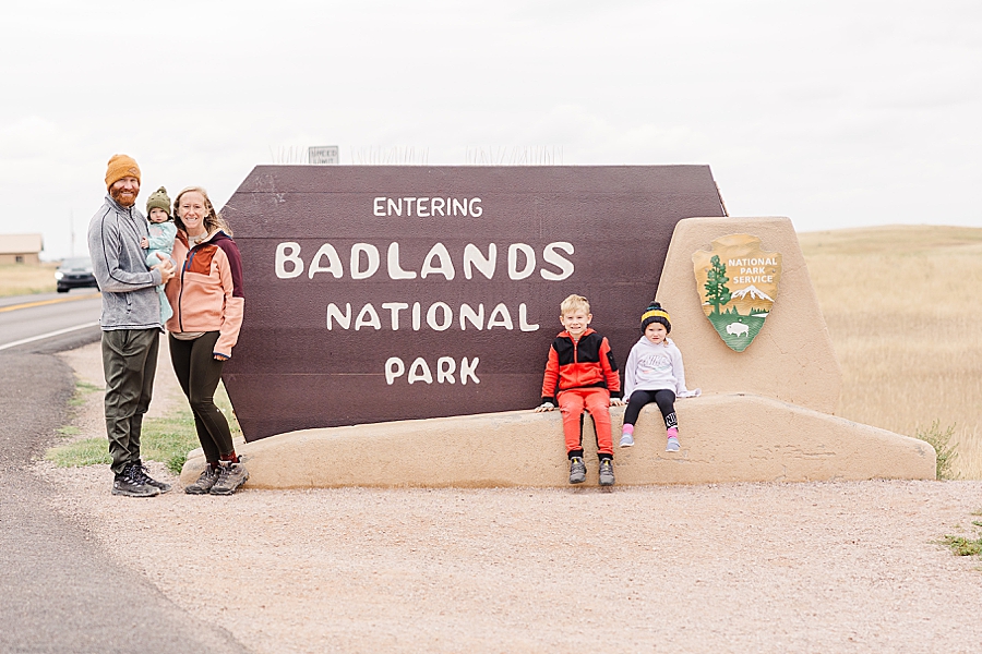 Family of five standing in front of badlands national park sign. 