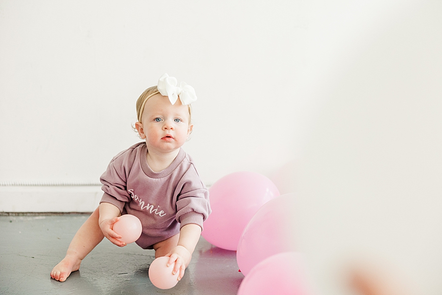 baby holding pink balls