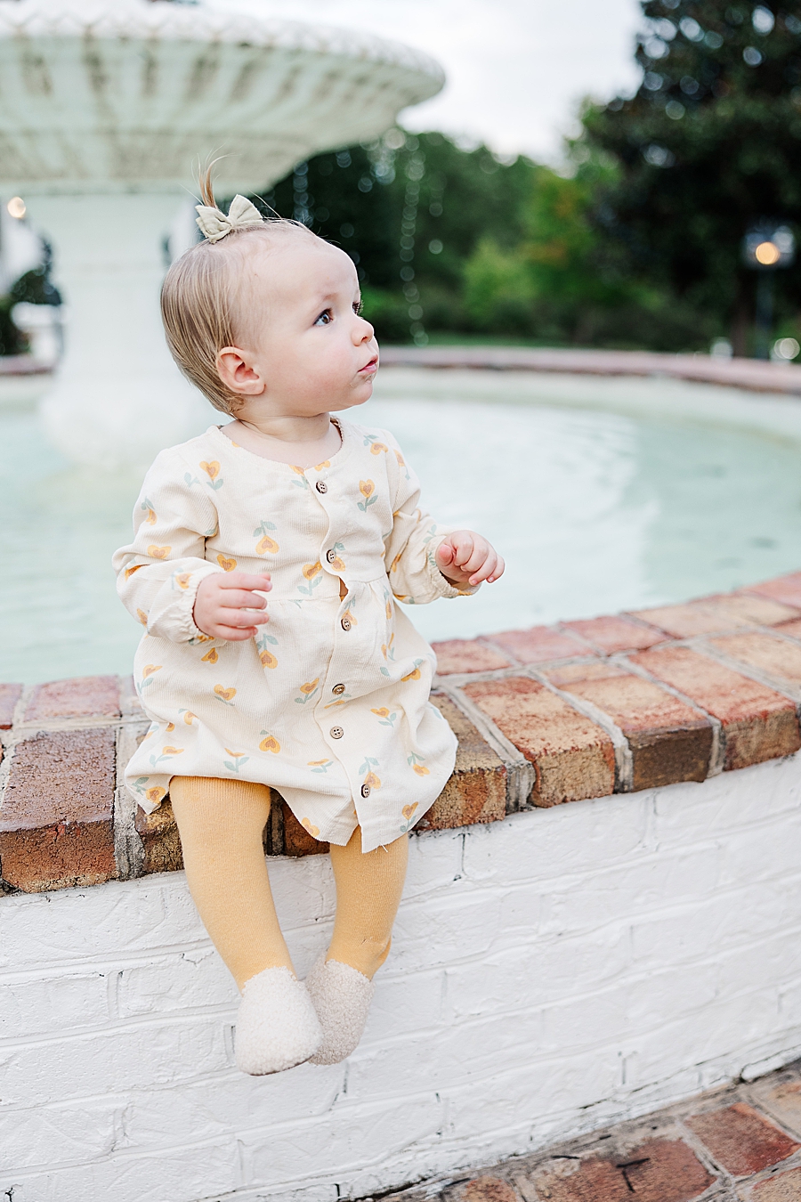 little girl sitting by fountain