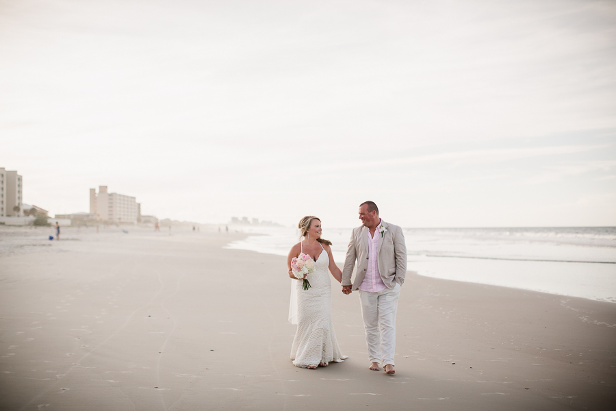 Walking holding hands on beach at this Daytona Beach Wedding by Destination Wedding Photographer, Amanda May Photos.