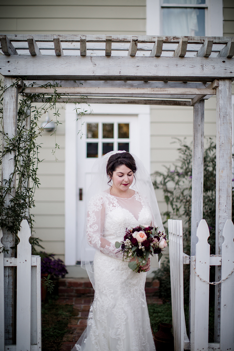 Looking down at her bouquet in between picket fence at this bridal session at The Barn at High Point Farms by Knoxville Wedding Photographer, Amanda May Photos.
