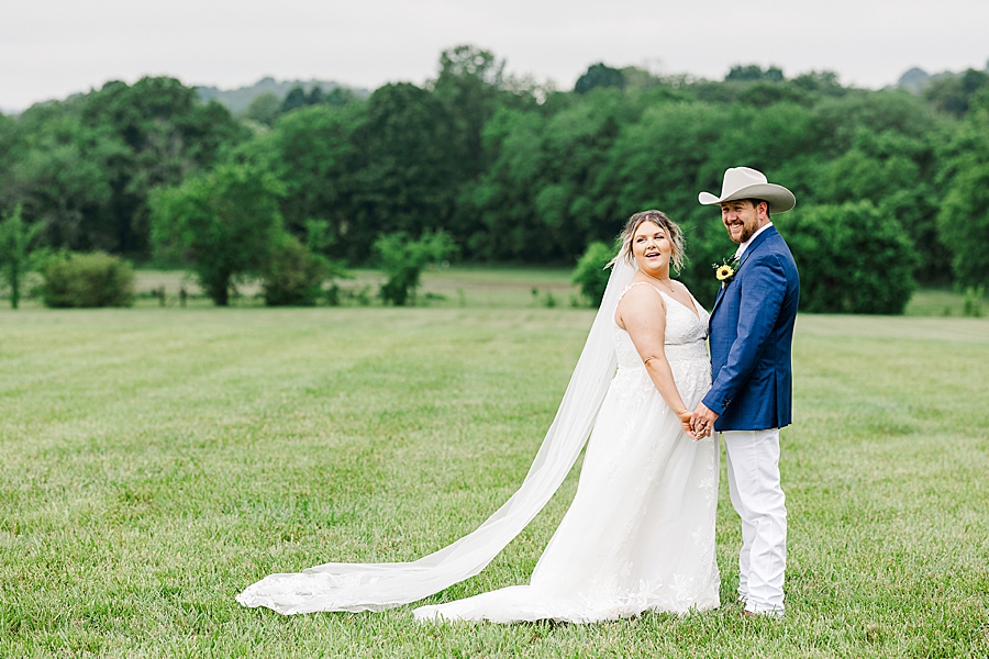 Bride and groom smile in a field at Allenbrooke Farm wedding by Amanda May Photos