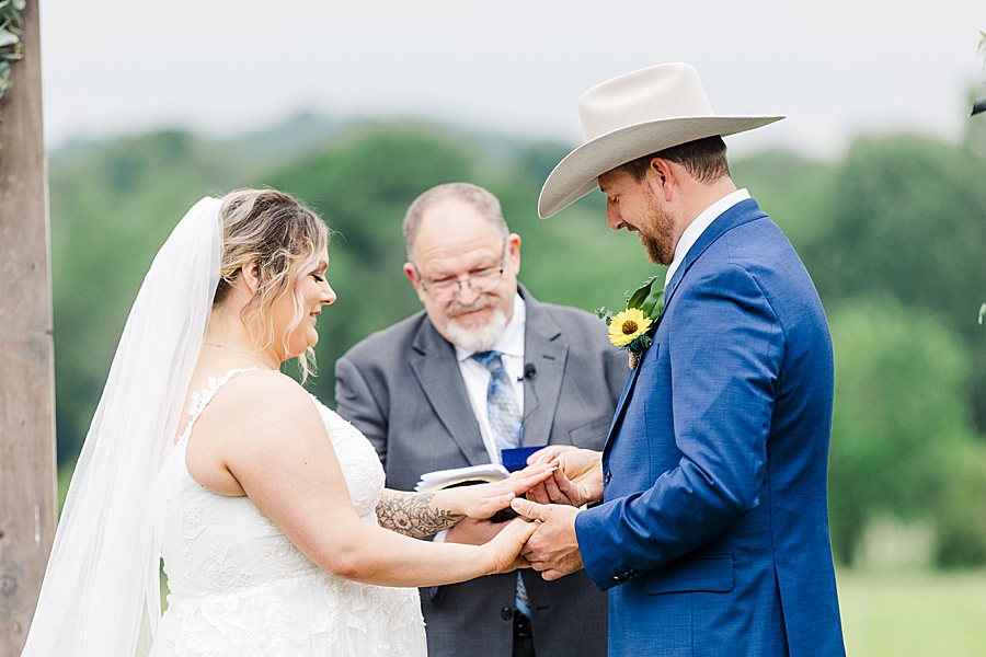 Groom placing ring on bride's finger at Allenbrooke Farm wedding by Amanda May Photos
