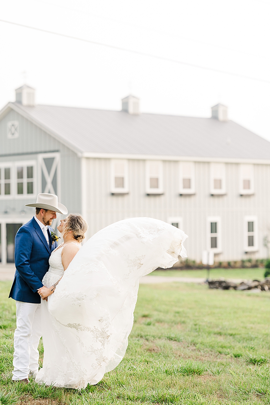 Standing in front of a barn at wedding by Amanda May Photos