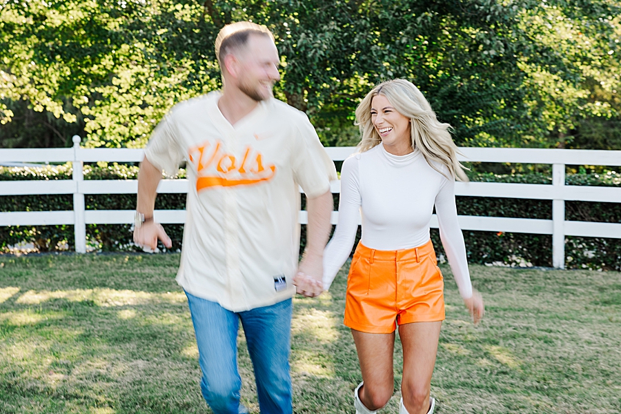couple in Vols outfits running at fall castleton farms engagement