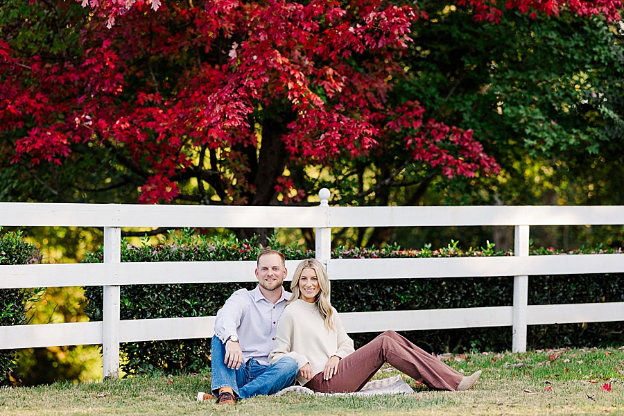 couple sitting by white picket fence