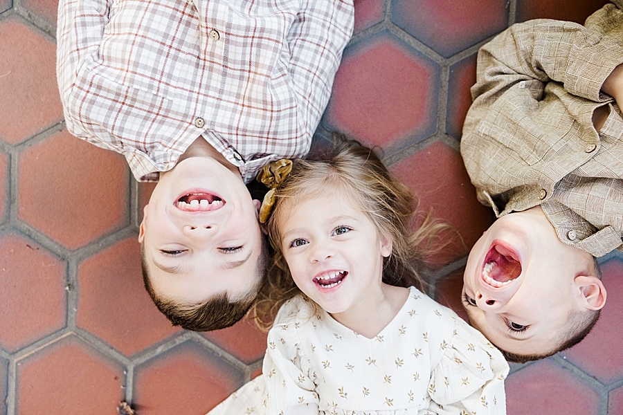 kids laying on red tile at fall family session
