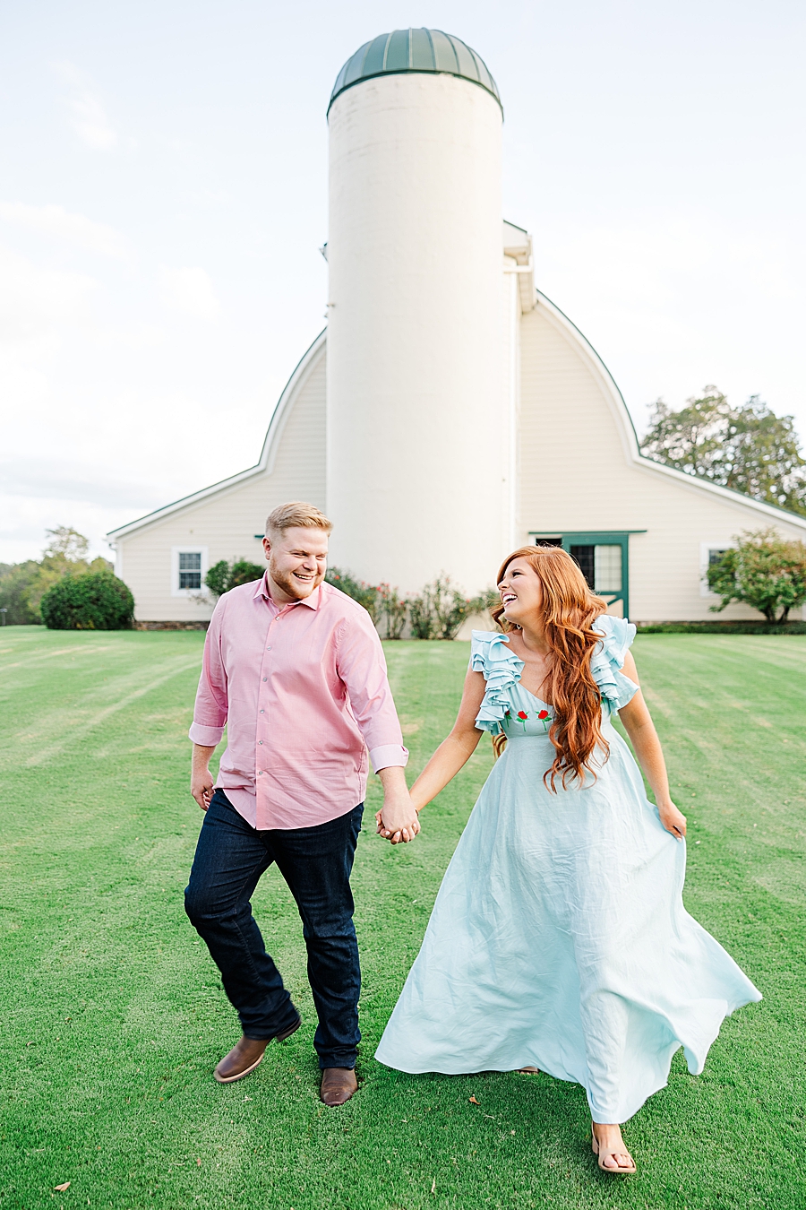 couple holding hands in front of silo