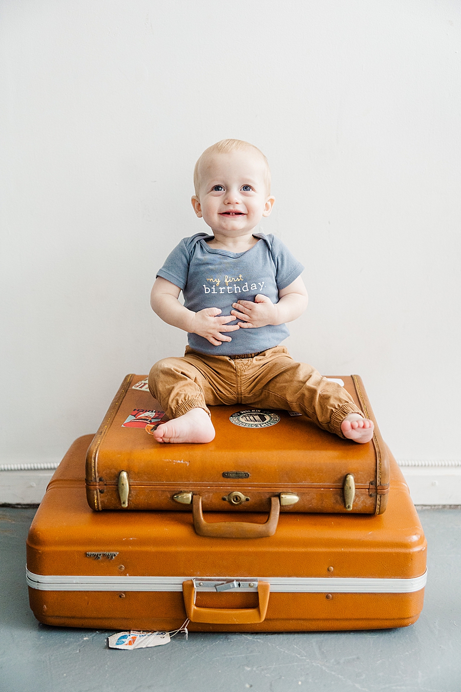 boy sitting on suitcases at first birthday