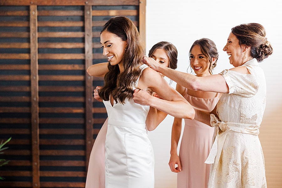 Mom and bridesmaids help with dress at Mill & Mine Wedding by Amanda May Photos