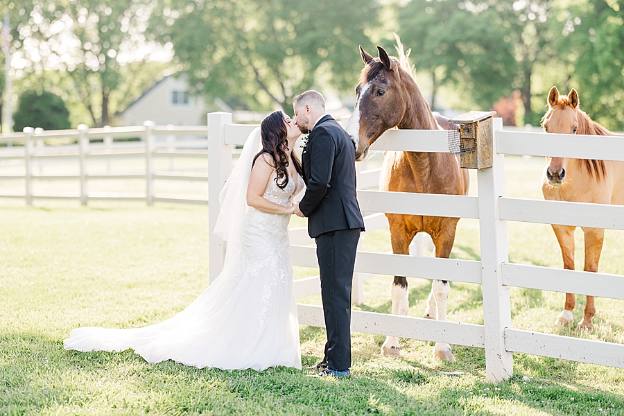 Kissing by the fence at wedding by Amanda May Photos
