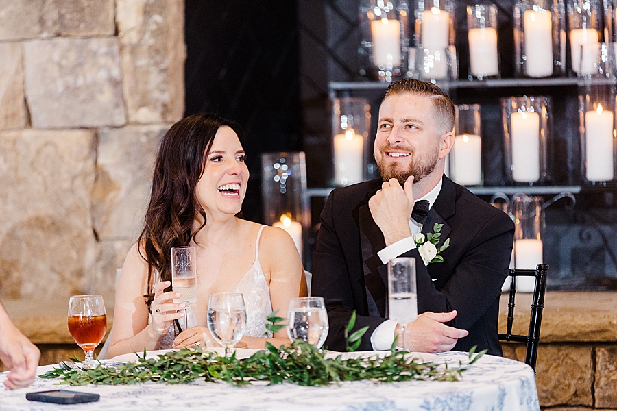 Bride and groom laughing at table at wedding by Amanda May Photos