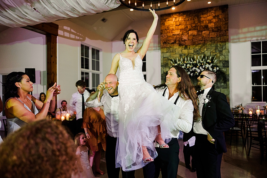 Groomsmen lift bride at wedding by Amanda May Photos