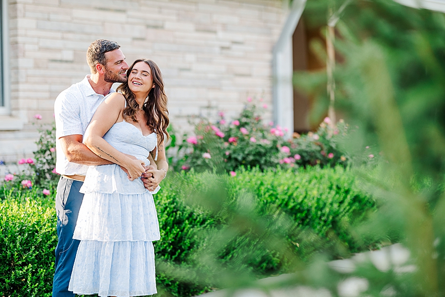 couple by pretty plants at lakeshore park engagement