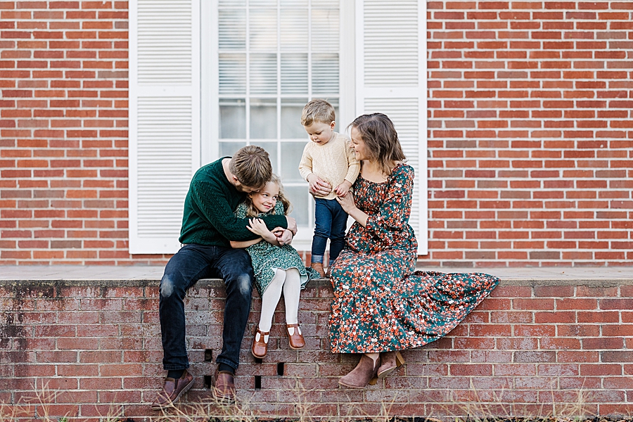 family sitting on brick wall