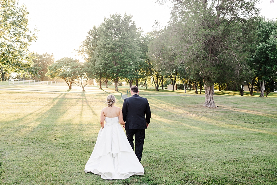 bride and groom walking through marblegate field