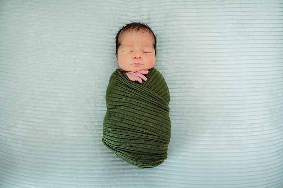 newborn in green swaddle