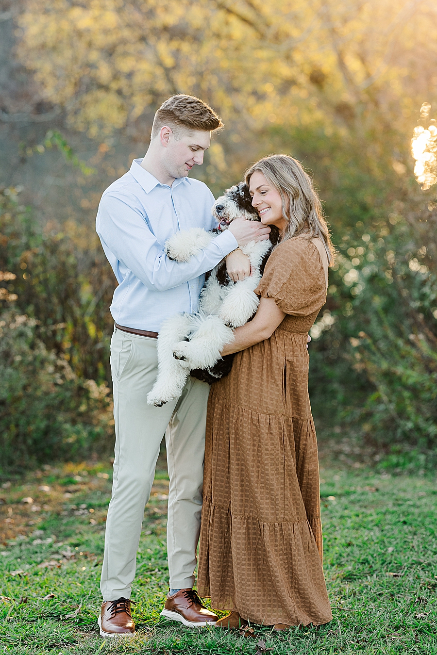 couple snuggling dog at park engagement