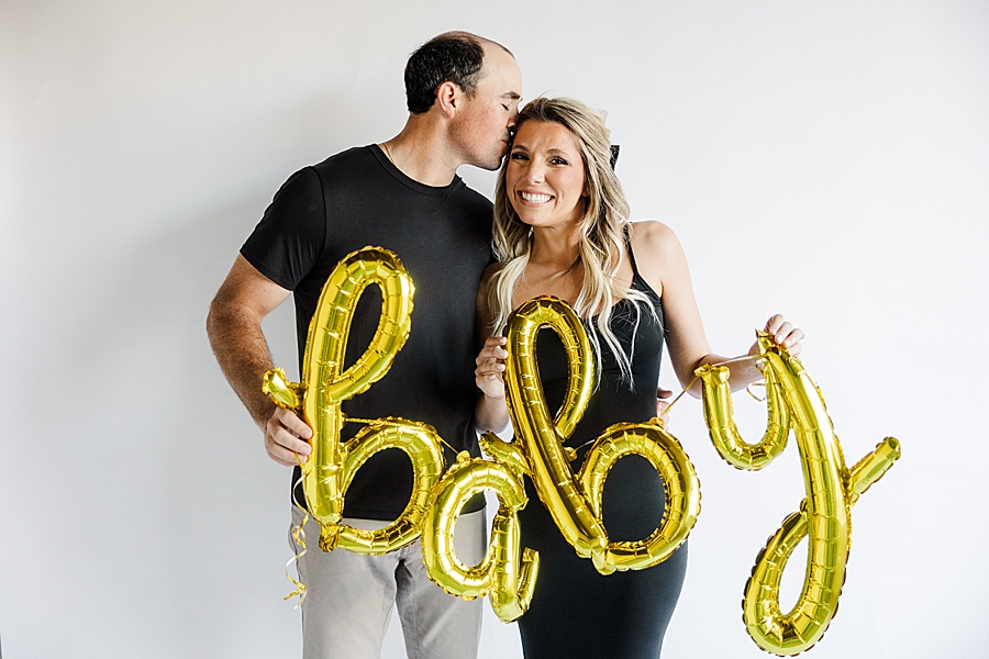couple holding baby balloons at pregnancy announcement