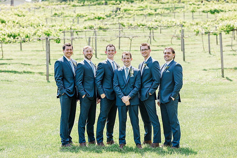 Groom and groomsmen smiling at camera at Ramble Creek wedding by Amanda May Photos