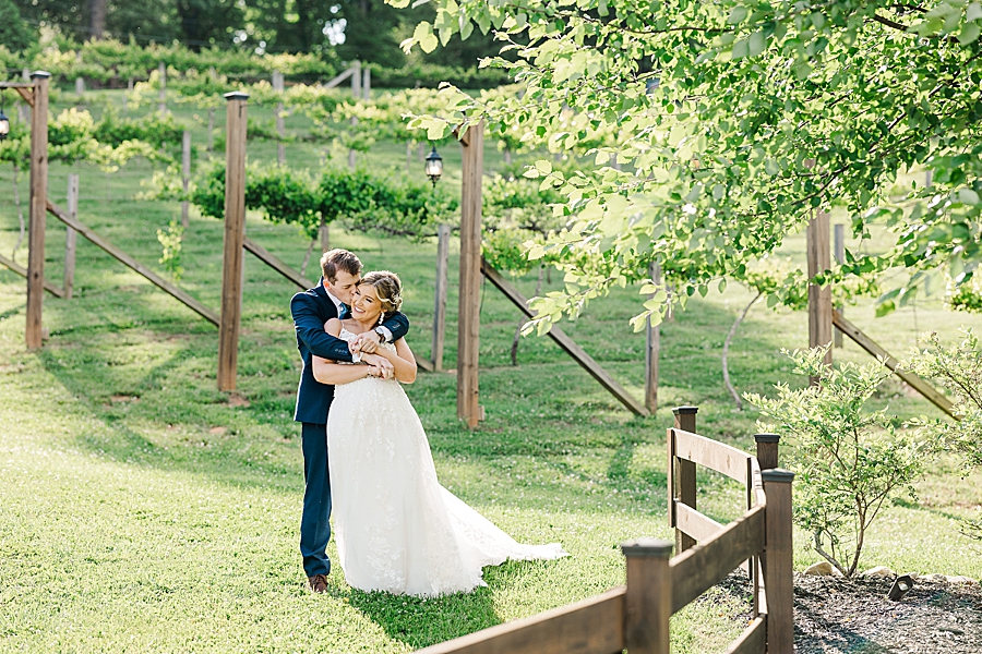 Groom kissing bride's cheek at wedding by Amanda May Photos