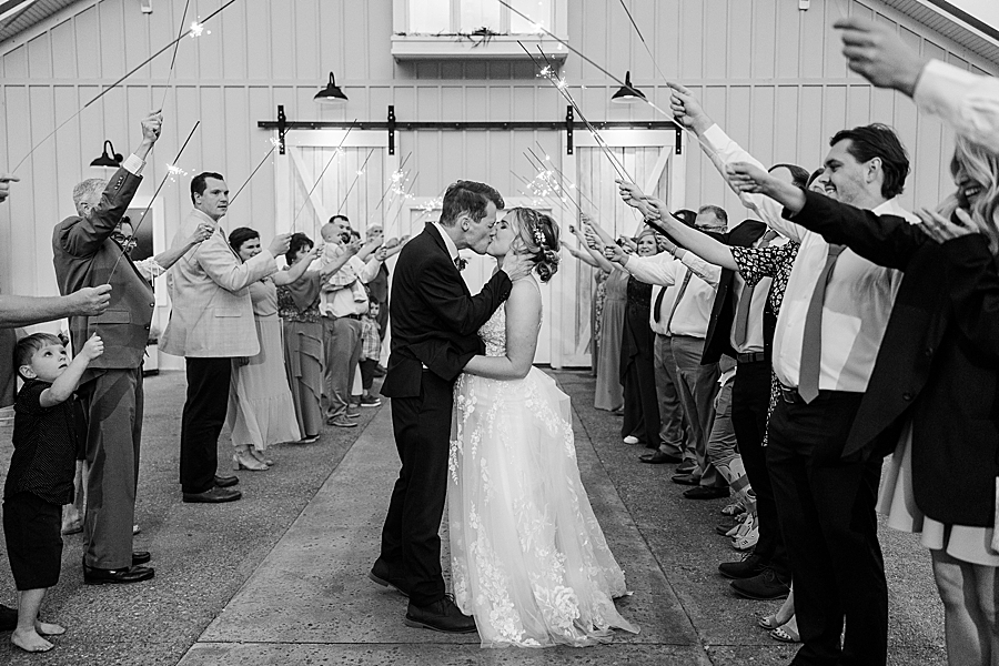 Bride and groom kiss under sparklers at wedding by Amanda May Photos