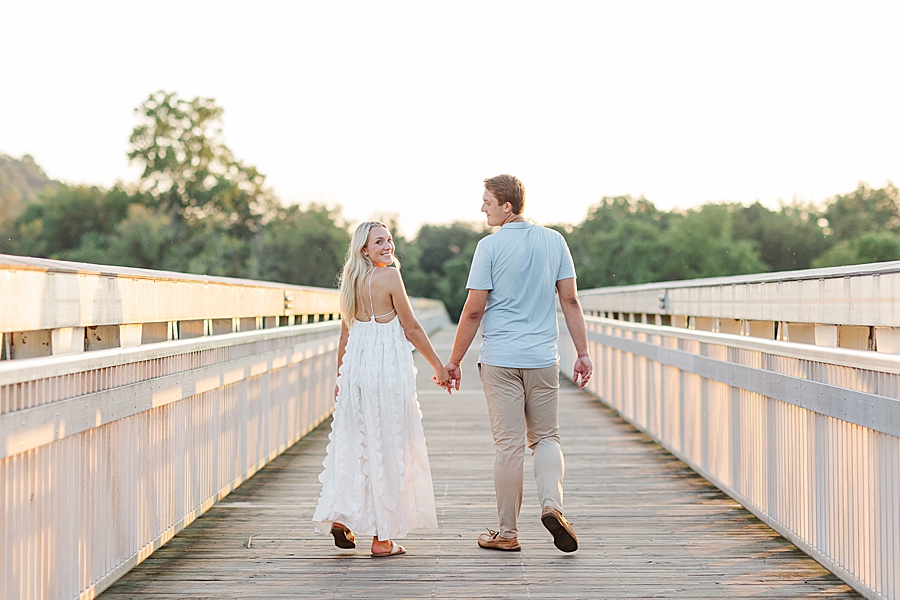 couple walking down boardwalk at seven islands engagement