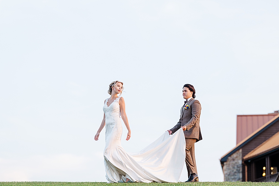 Groom holding bride's dress and walking at styled shoot by Amanda May Photos