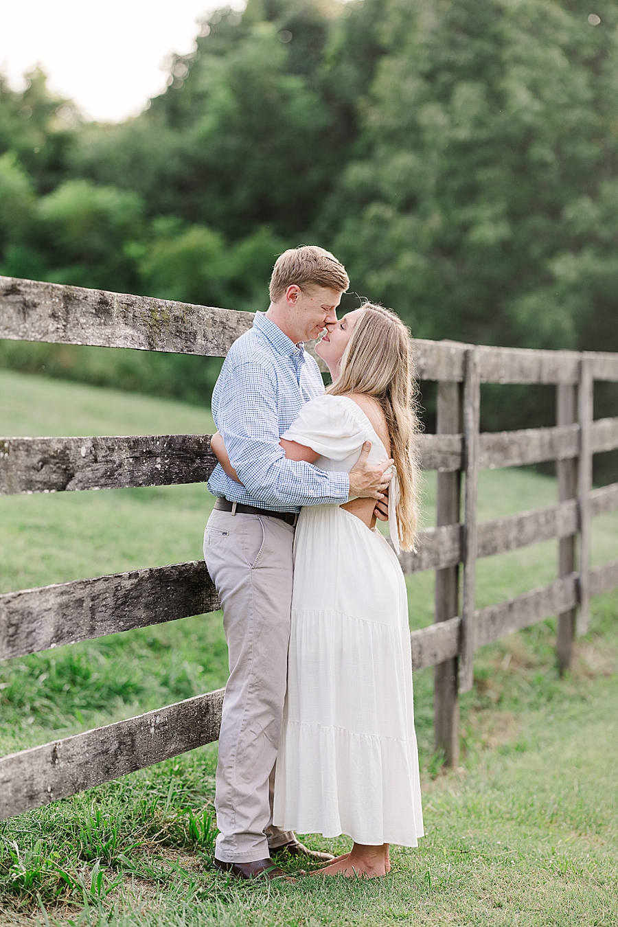 couple standing by fence at sunset engagement session