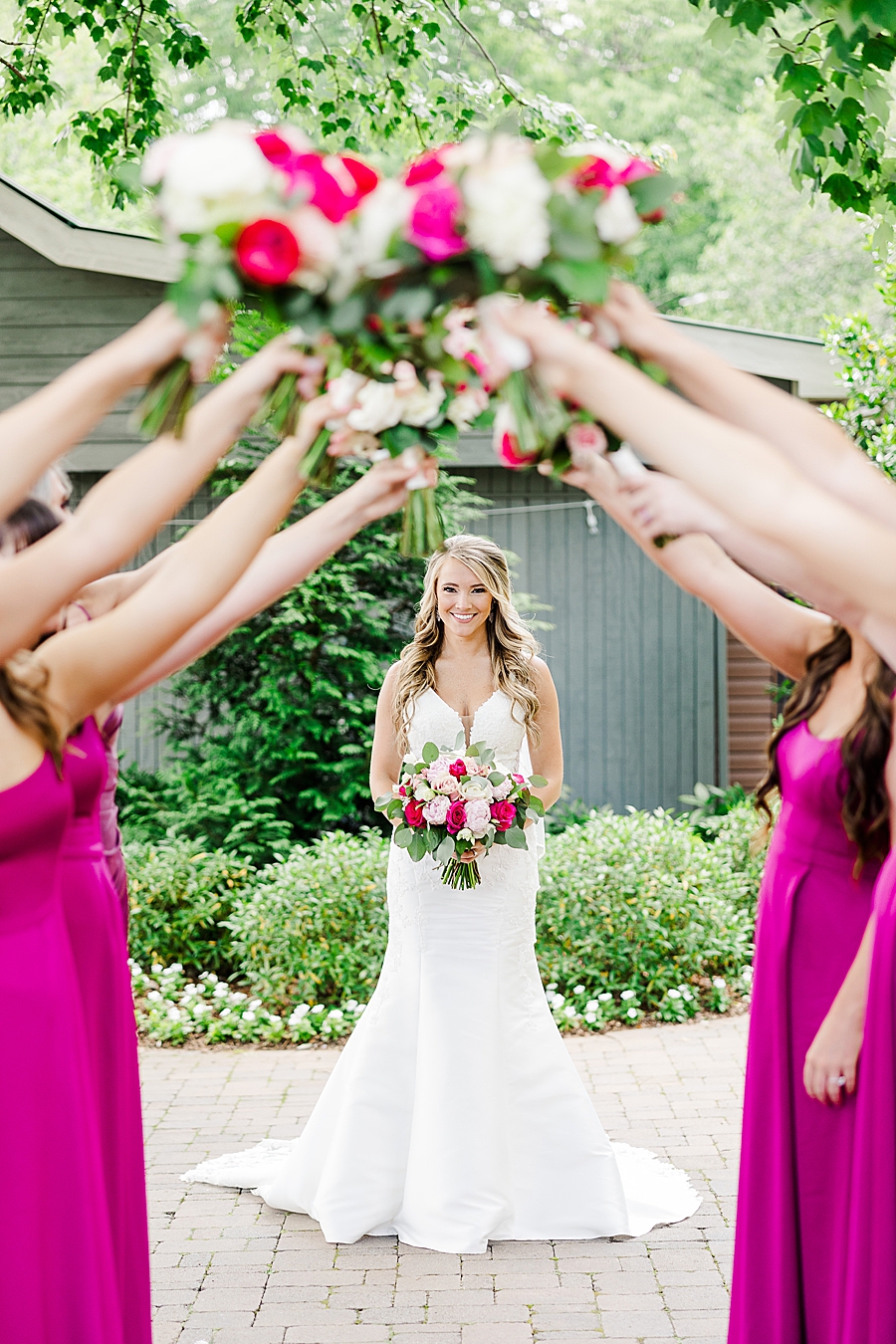 bridesmaids holding bouquets over bride